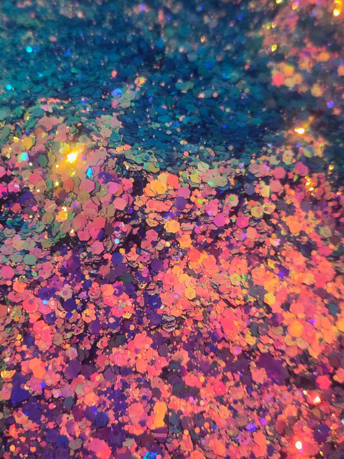 Close-up of iridescent glitter flakes with a color-shifting finish, showing a mix of pink, purple, orange, blue, and gold tones.