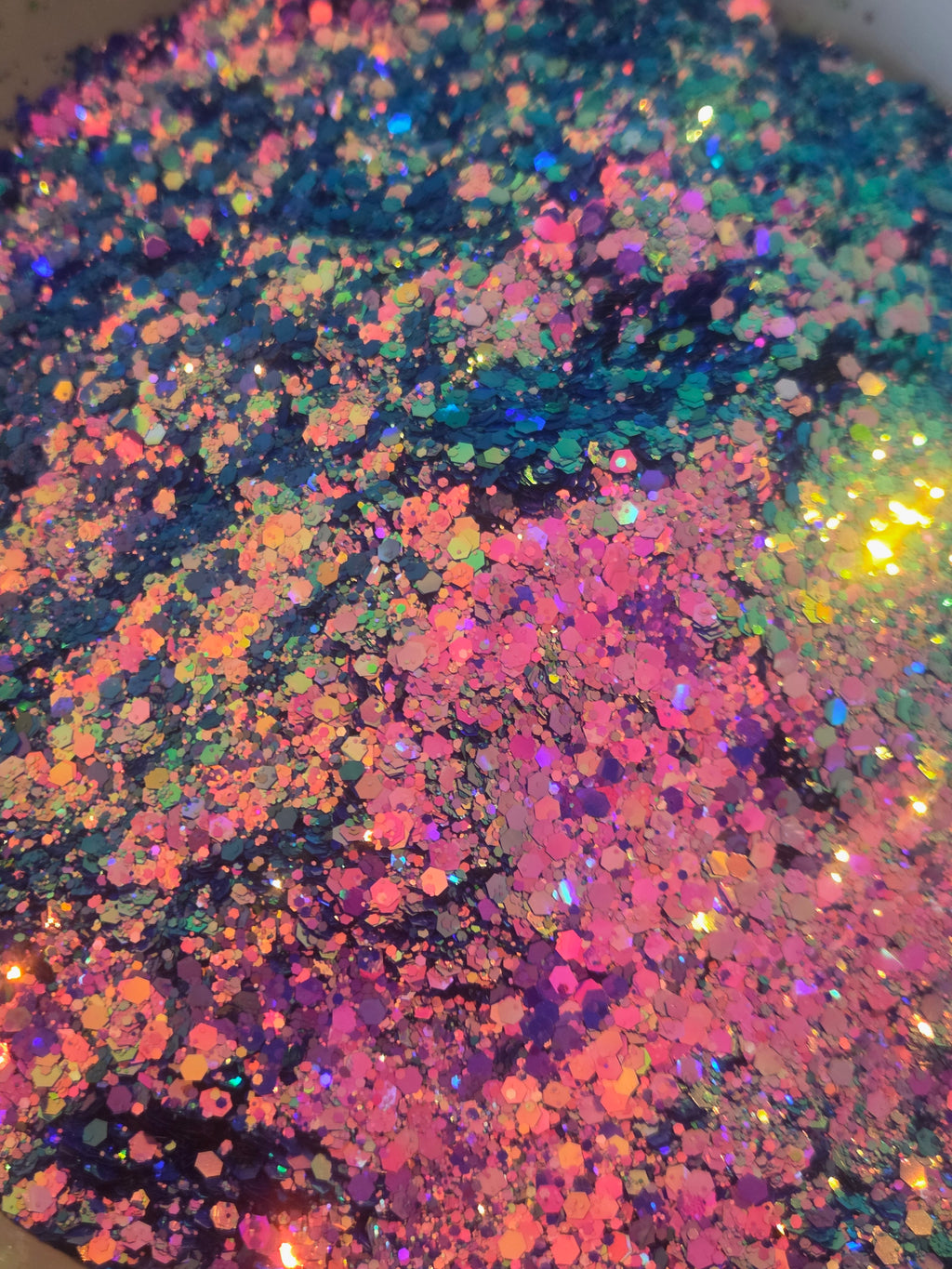 Close-up of iridescent glitter flakes in a mix of pink, purple, blue, green, orange, and yellow tones.